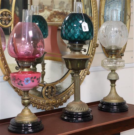 Three Edwardian brass and glass oil lamps, two with coloured glass shades